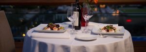 imagen-de-cena-romantica-en-terraza-mesa-servida-copas-botella-de-vino-y-flor-naranja