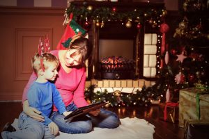 mother and son using tablet pc by a fireplace