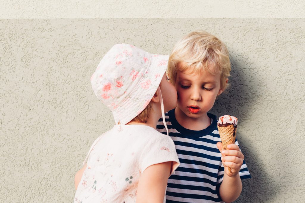 Niña dando un beso a un niño con helado