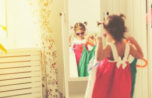 girl child looks into the mirror and choose dresses
