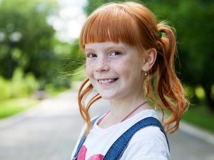 Close up portrait of a smiling ginger girl with freckles
