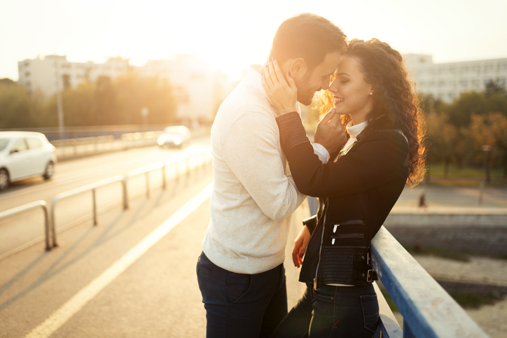 pareja se besa en un puente al atardecer