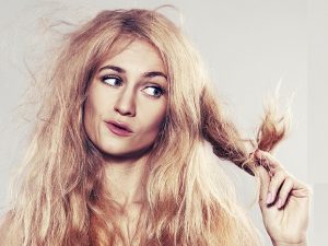 Young woman looking at split ends. Damaged long hair