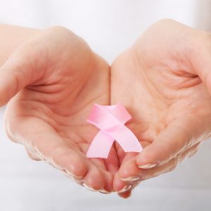 Close-Up Midsection Of Woman Holding Breast Cancer Awareness Ribbon