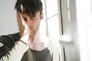 Young man with eyes closed and hand on his face
