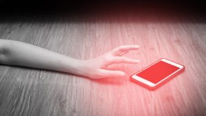 womans hand reaches for mobile phone with red spot. Emergency concept