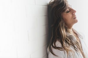 Close-Up Of Sad Woman Standing Against White Brick Wall