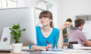 frau mit apfel am computer in buro, munchen, bayern, deutschland