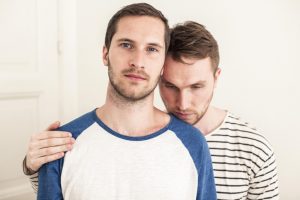 Portrait of young gay man with loving partner at home