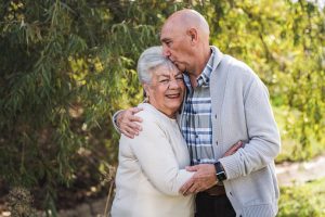 Portrait of grandfather kissing his mothers forehead outside