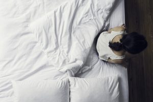 Woman sitting on side of bed waking up
