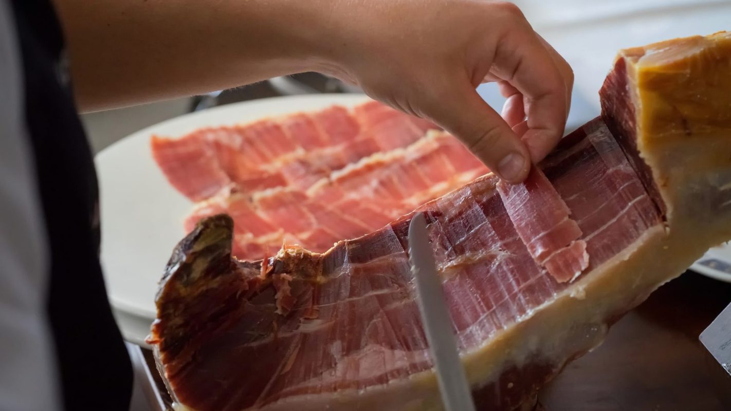 Un concursante de MasterChef Uruguay coge jamón para picar durante la prueba