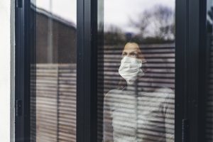 Woman with mask looking out of window