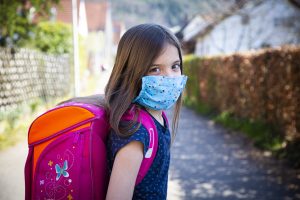 niña con mascarilla y mochila al colegio