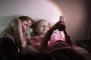 hermanas miran el movil en la cama