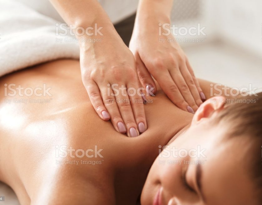 Young woman enjoying therapeutic neck massage in spa center, closeup