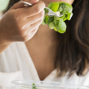 Crop view of young architect eating mixed salad at desk