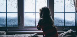 niña nevada mira por la ventana