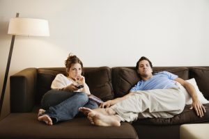 Young couple on sofa watching television.
