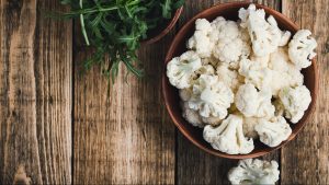 Fresh organic cauliflower cut into small pieces in a bowl. Vegetarian recipe or menu background with copy space