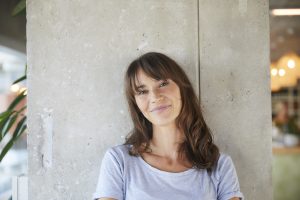 Smiling woman standing against concrete wall at home