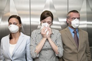 Una mujer estornuda en el ascensor.