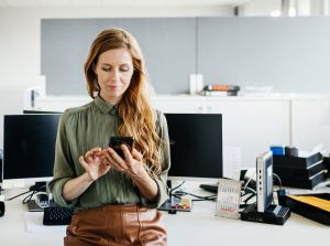Mujer consulta su móvil en la oficina.