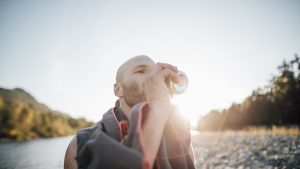 Canada, British Columbia, Chilliwack, man drinking from can at Fraser River