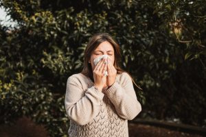 Persona estornudando en primavaera por la alergia al polen.