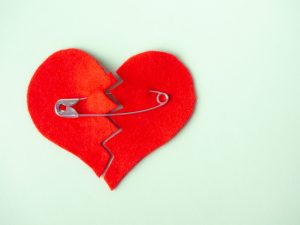 Un corazón de tela partido es unido con un imperdible.