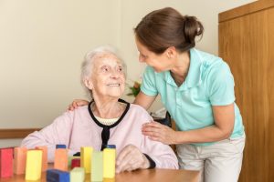 Una auxiliar cuida de una mujer mayor enferma de Alzheimer.