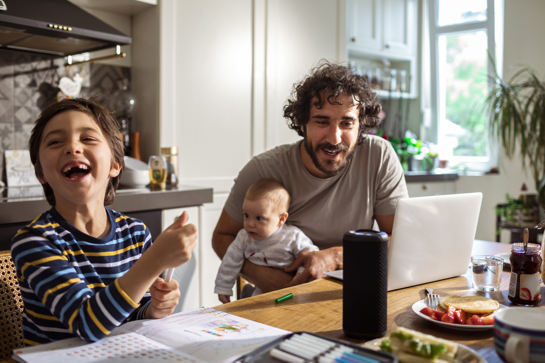 Un padre juega con sus dos pequeños en casa.