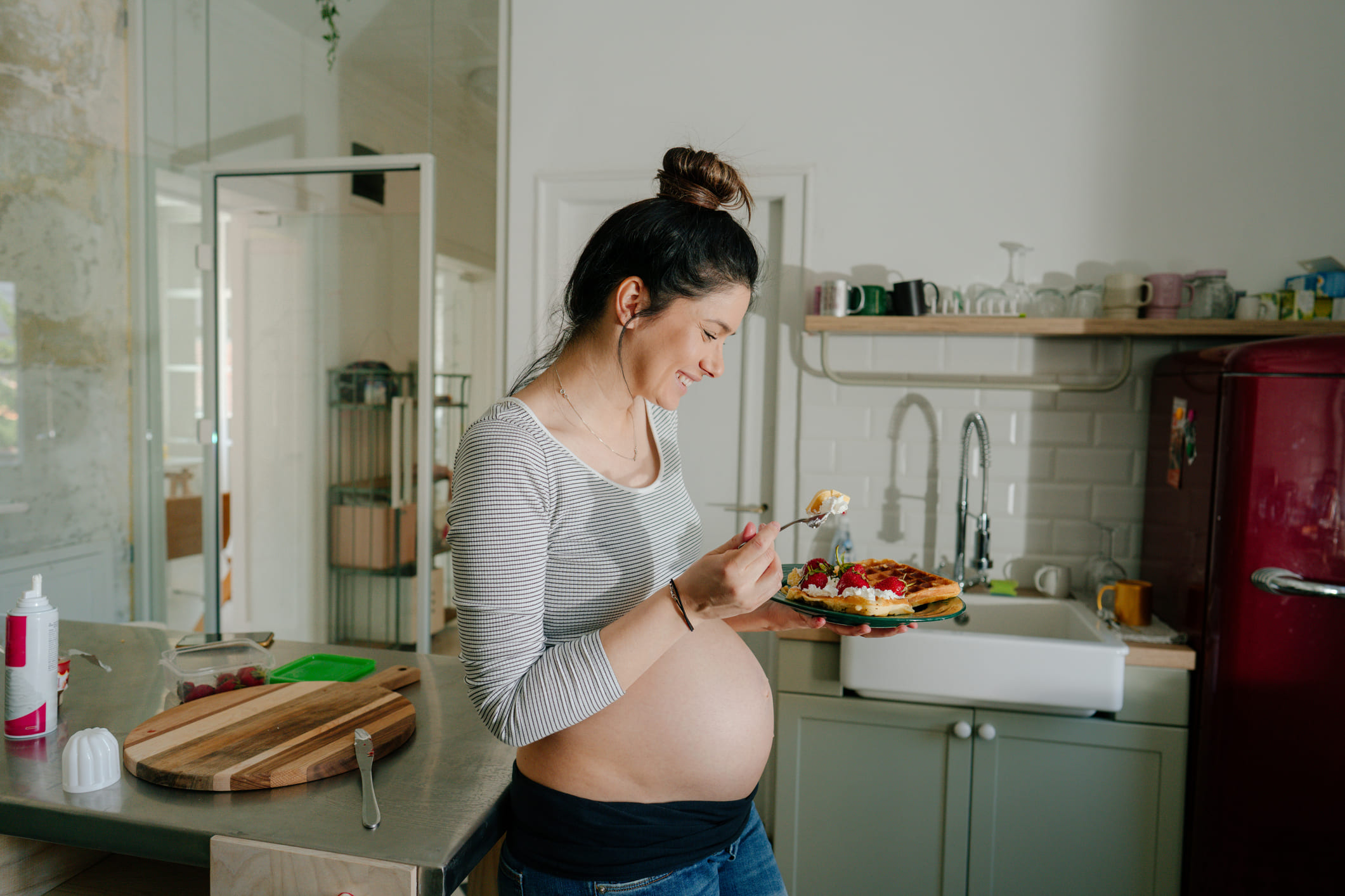 Una mujer feliz satisfaciendo su antojo de dulce durante el embarazo con un gofre.
