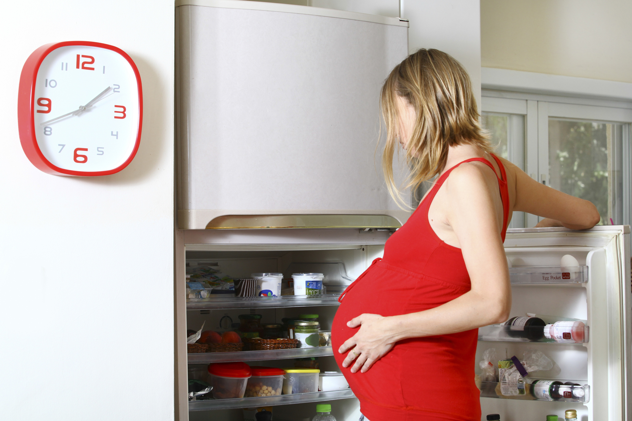 Una mujer embarazada mira en la nevera qué tiene para satisfacer su antojo.