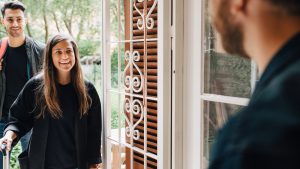 Midsection of male owner greeting guests at doorway of rental apartment