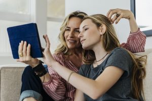 Madre e hija charlan animadamente viendo algo en un dispositivo electrónico.