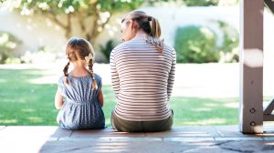 Madre e hija charlan amablemente sobre la asertividad en las escaleras de su casa.