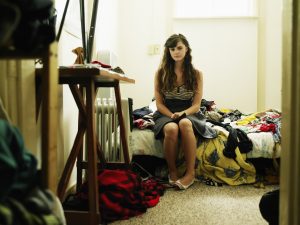 Portrait young woman sitting on bed in bedroom