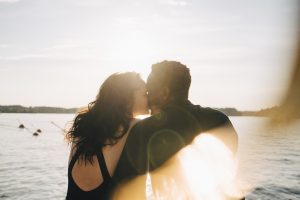 Una pareja se da un tierno beso al atardecer en el mar.