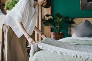 Una joven ordena y estira las fundas de su cama tras lavar las sábanas.