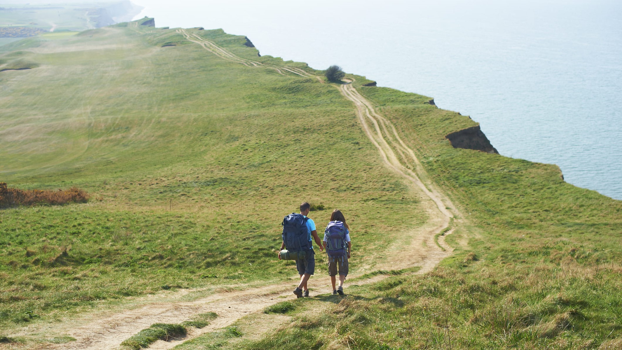 Dos amigos pasean plácidamente al lado del mar.