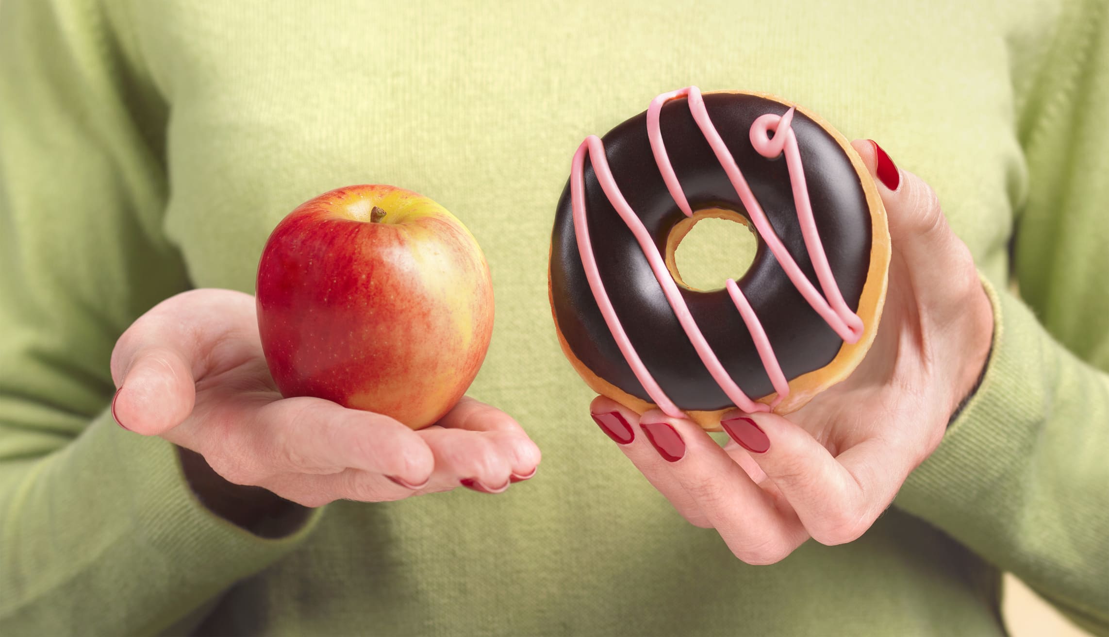 Una chica debate sobre si comerse un donut o una manzana.