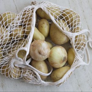 Una bolsa repleta de patatas y cebollas.