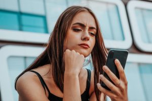 Una chica mira la pantalla de su móvil porque ha recibido un viaje de su crush.