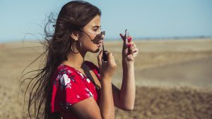 Teenage girl applying lip gloss on the beach