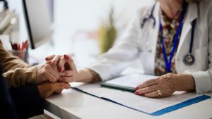 Shot of an unrecognizable doctor holding hands with her patients during a consultation