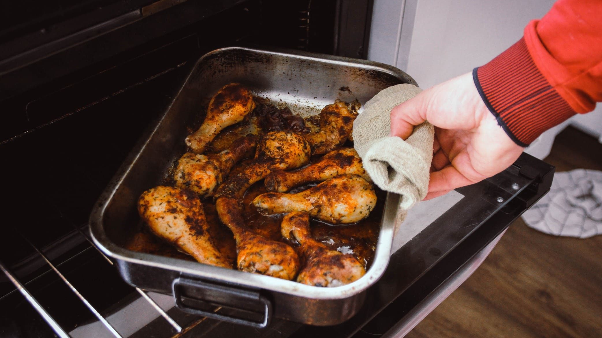 Una persona cocinando en su casa pollo al horno.