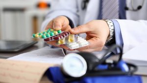 GP in clinic holding pack of different blisters