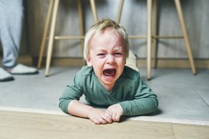 Un niño llora tirado en el suelo.