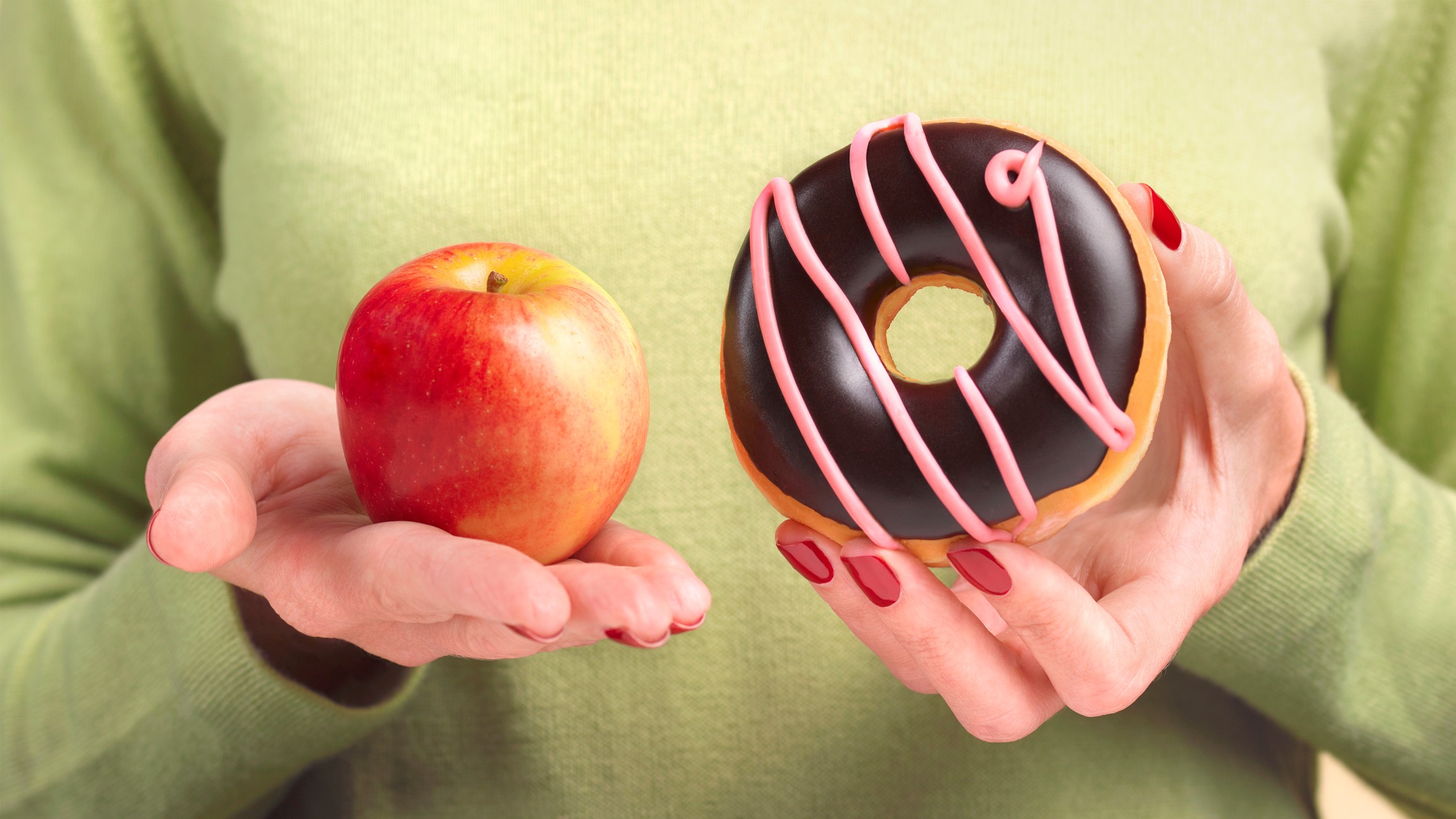 Una chica elige si comer un donut o una manzana.